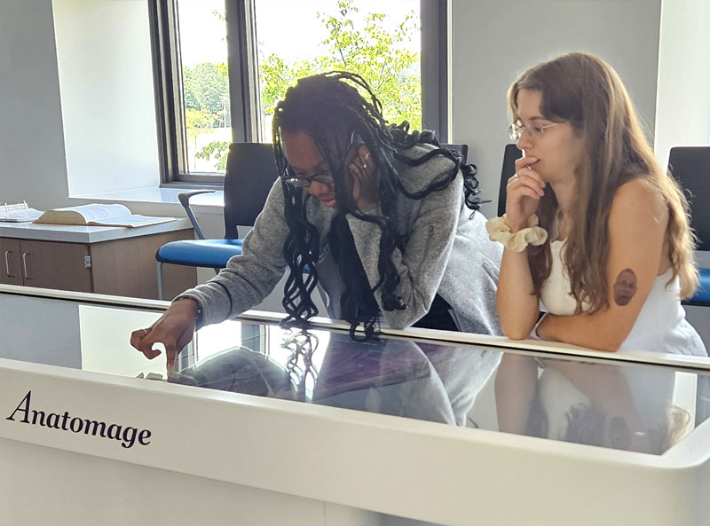 2 students actively engaging with the Anatomage Table.