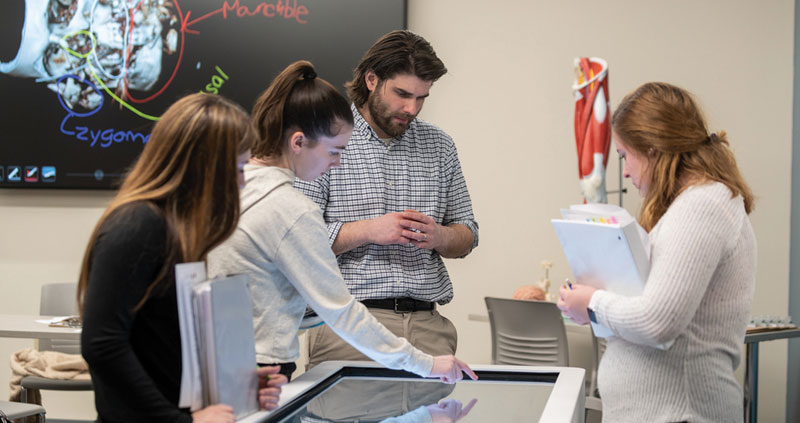 A professor and students interacting with the Anatomage Table.